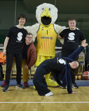 Die Sonnenstich-Artisten Elias Massing, Florian Klotz, Sol Rein-Saunders und Luzian Bücker nehmen das körpergroße Alba Maskottchen in die Mitte