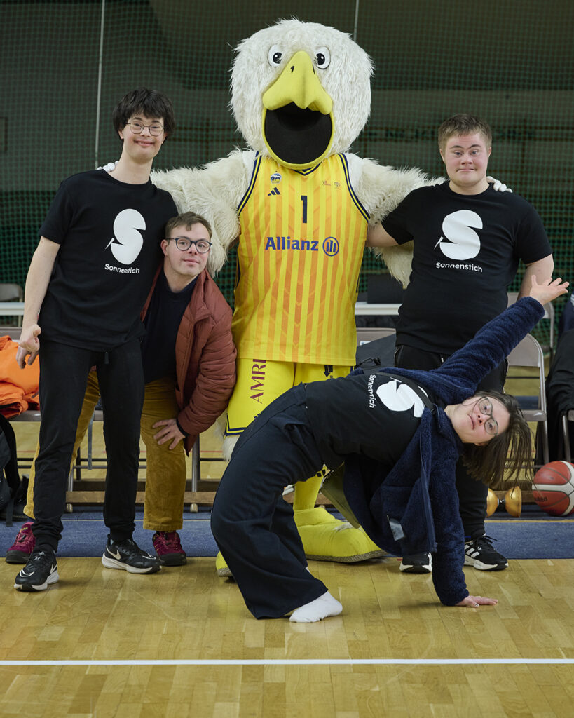 Die Sonnenstich-Artisten Elias Massing, Florian Klotz, Sol Rein-Saunders und Luzian Bücker nehmen das körpergroße Alba Maskottchen in die Mitte