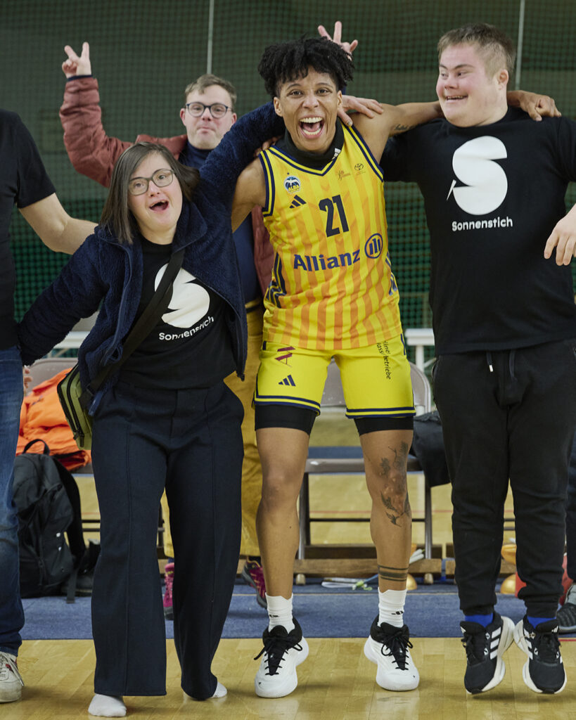 Die Sonnenstich-Artisten Sol Rein-Saunders, Florian Klotz und Luzian Bücker bejubeln Arm in Arm mit Basketball-Spielerin Deeshyra Thomas den Sieg von Alba Berlin über den MBC Halle