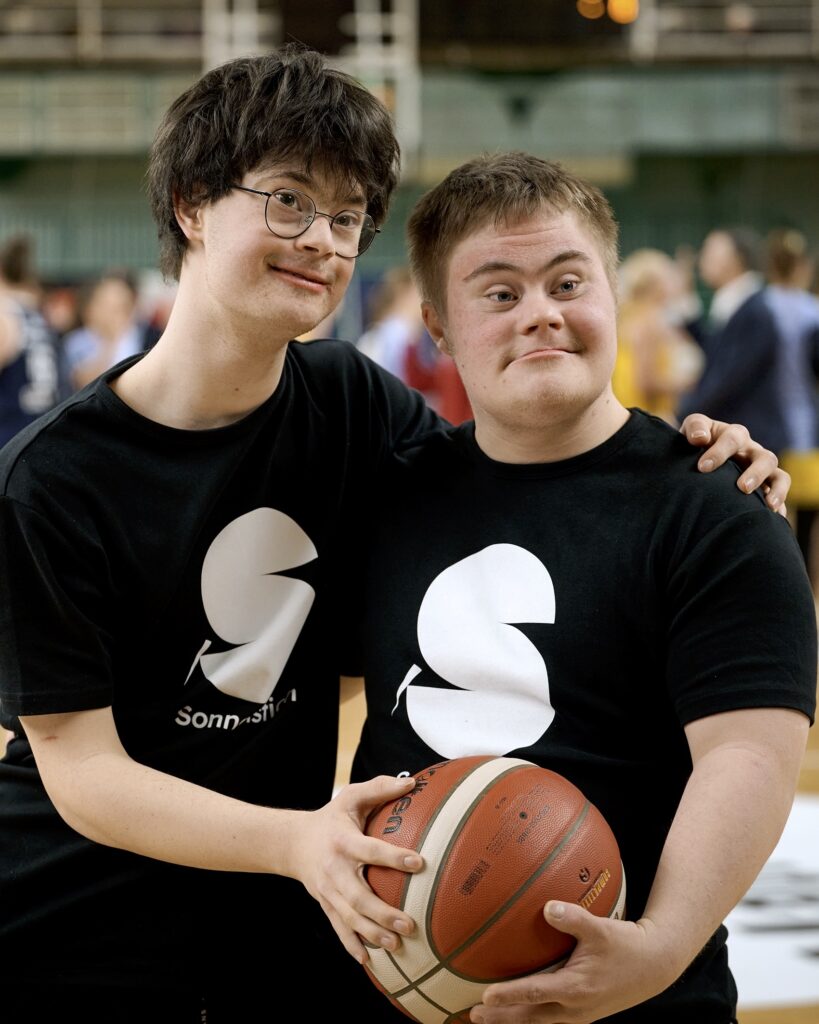 Nach dem Spiel von Alba Berlin gegen MBC Halle sind Elias Massing (links) und Luzian Bücker in Großaufnahme und Arm in Arm mit dem Basketball in der Hand zu sehen