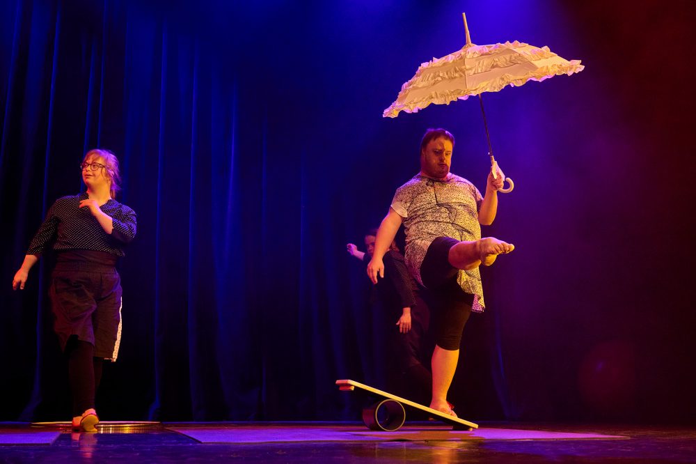 Christian Wollert balanciert mit Schirm auf dem Balken